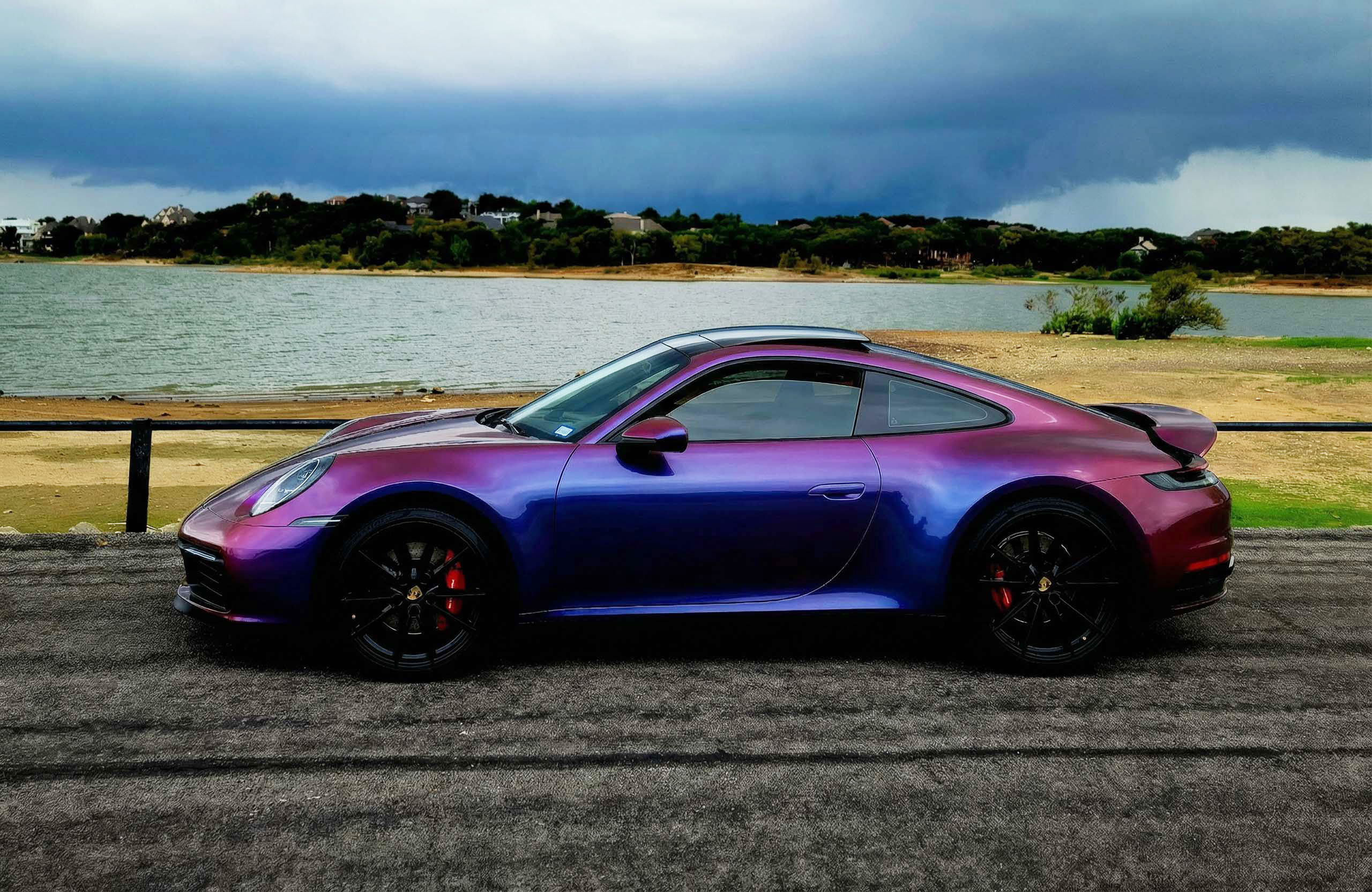 Porsche 911 wrapped in Avery Gloss Roaring Thunder Blue Red on a lakeside road